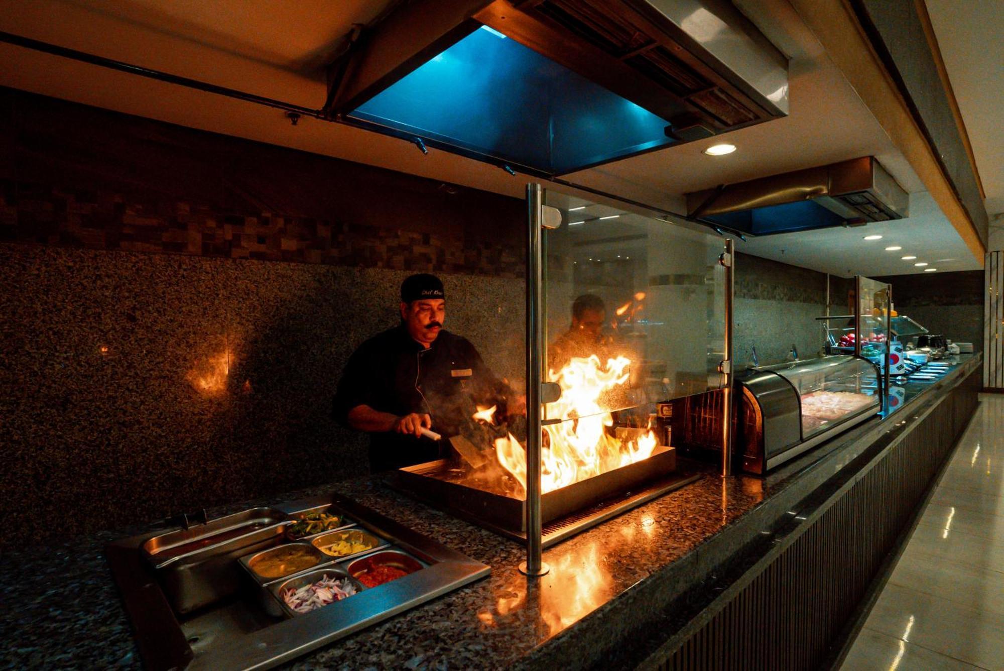 The V Luxury Resort Sahl Hasheesh 洪加達 外观 照片 A chef cooking with a flaming torch