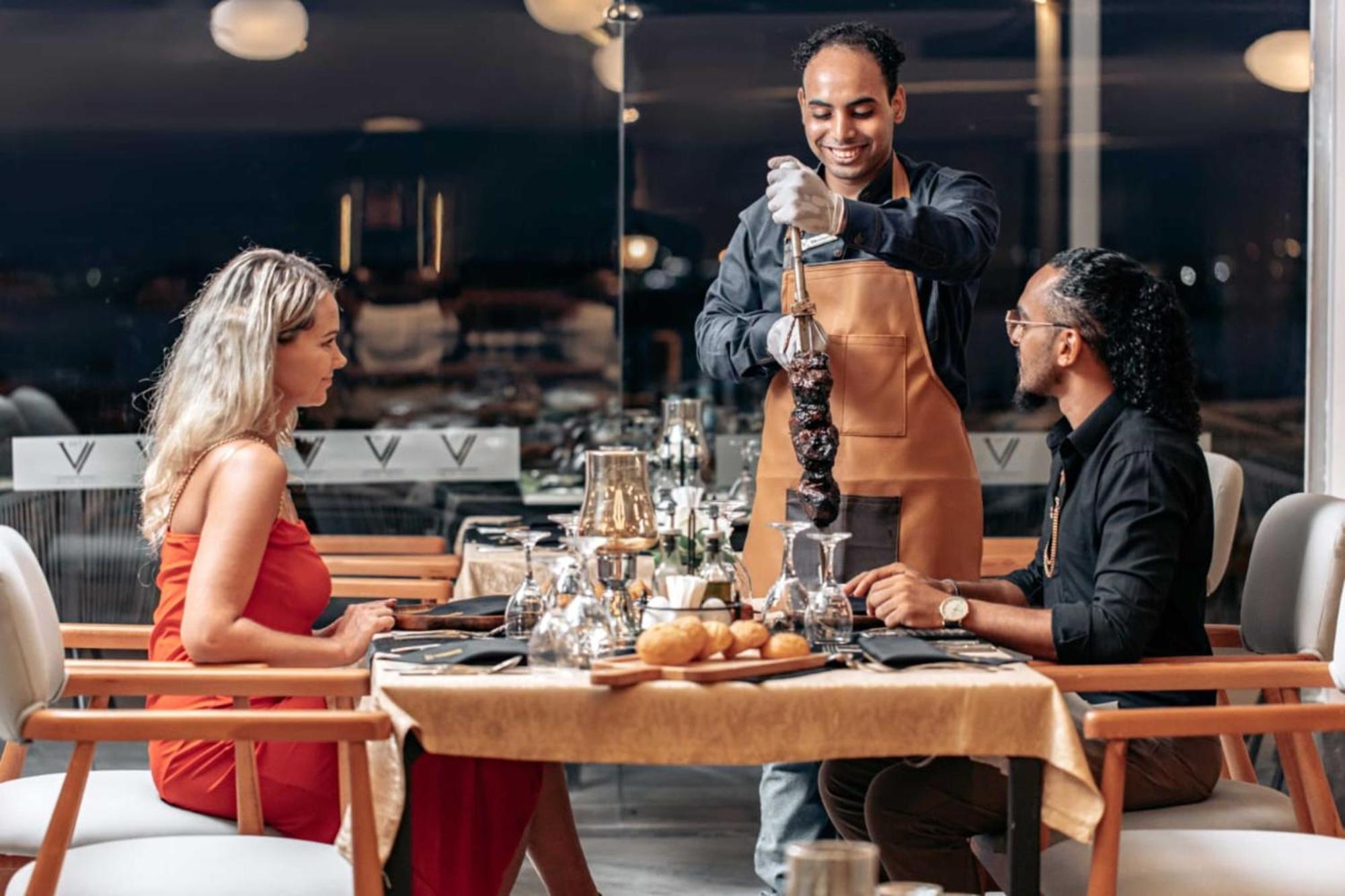 The V Luxury Resort Sahl Hasheesh 洪加達 外观 照片 A waiter serving a couple at a restaurant